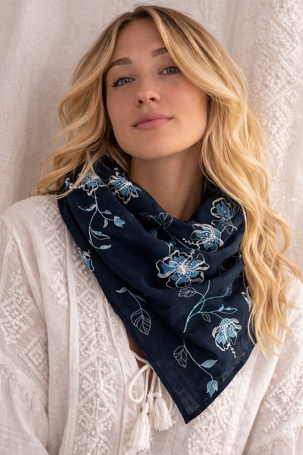 Woman wearing a navy blue floral embroidered scarf against a neutral background