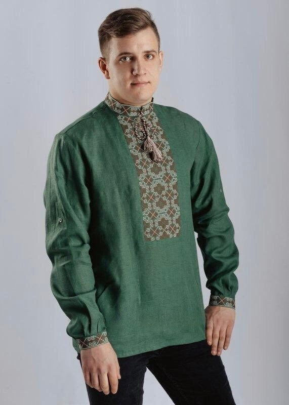 A man wearing a green linen vyshyvanka shirt with white embroidery, featuring long sleeves and a stand collar.