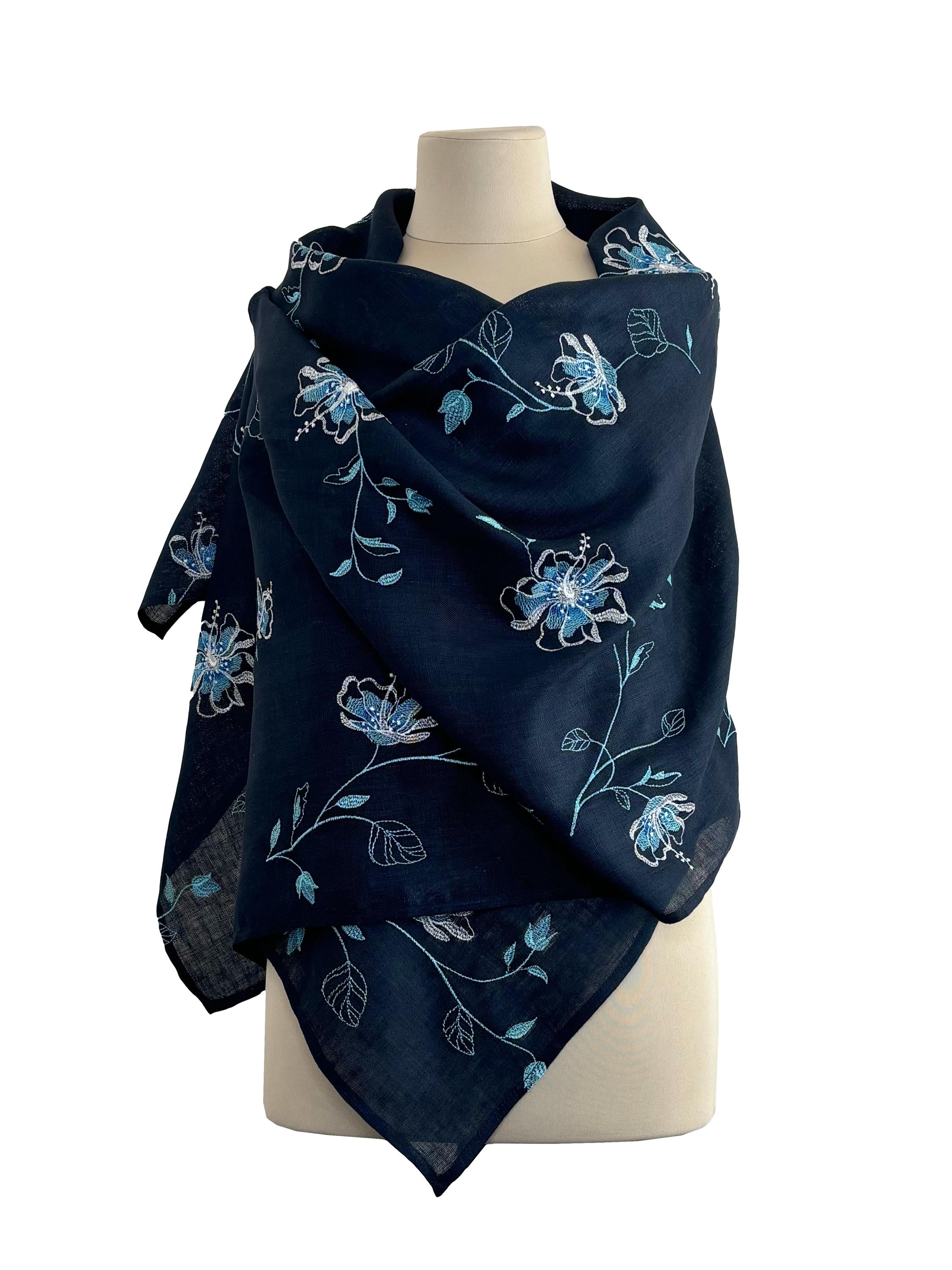 A blue Ukrainian shawl with white floral embroidery displayed on a mannequin.