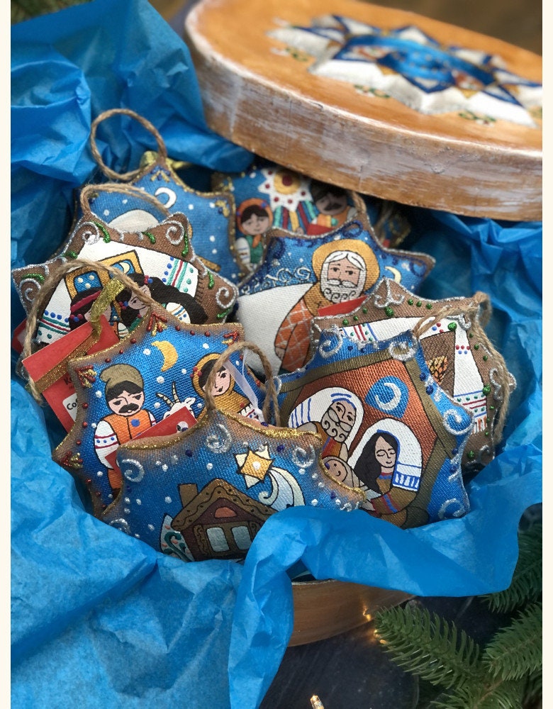 A set of Ukrainian Christmas tree decorations featuring the Holy Family with a blue background, placed on a wooden surface.