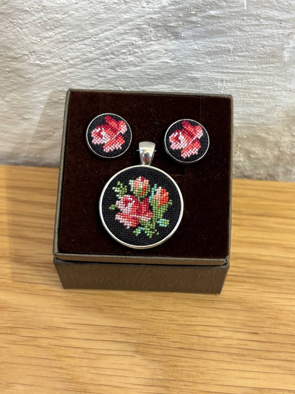 set of embroidered earrings and pendant displayed in a box, featuring red floral patterns