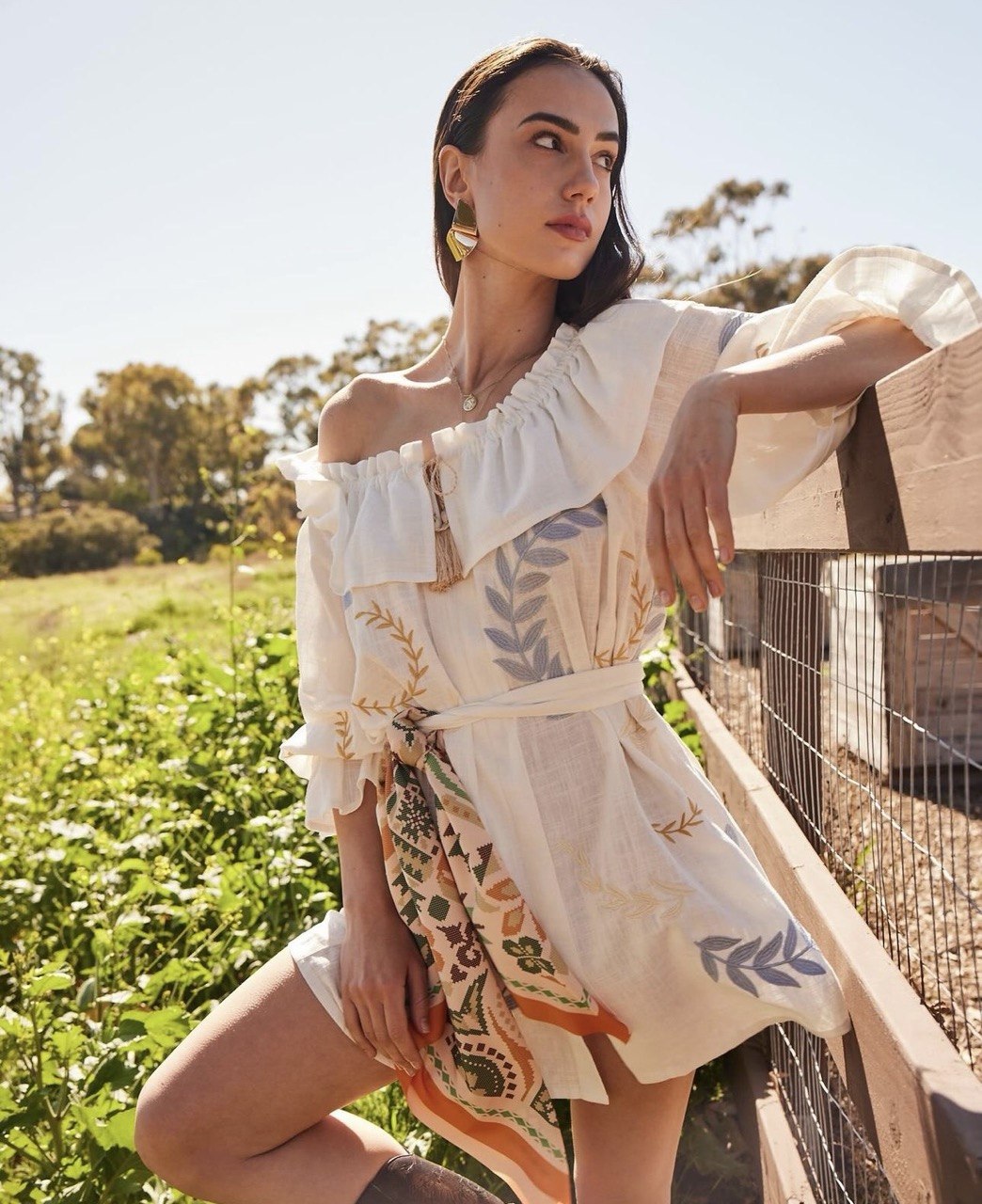 bohemian-style off-the-shoulder white dress with a printed scarf tied at the waist