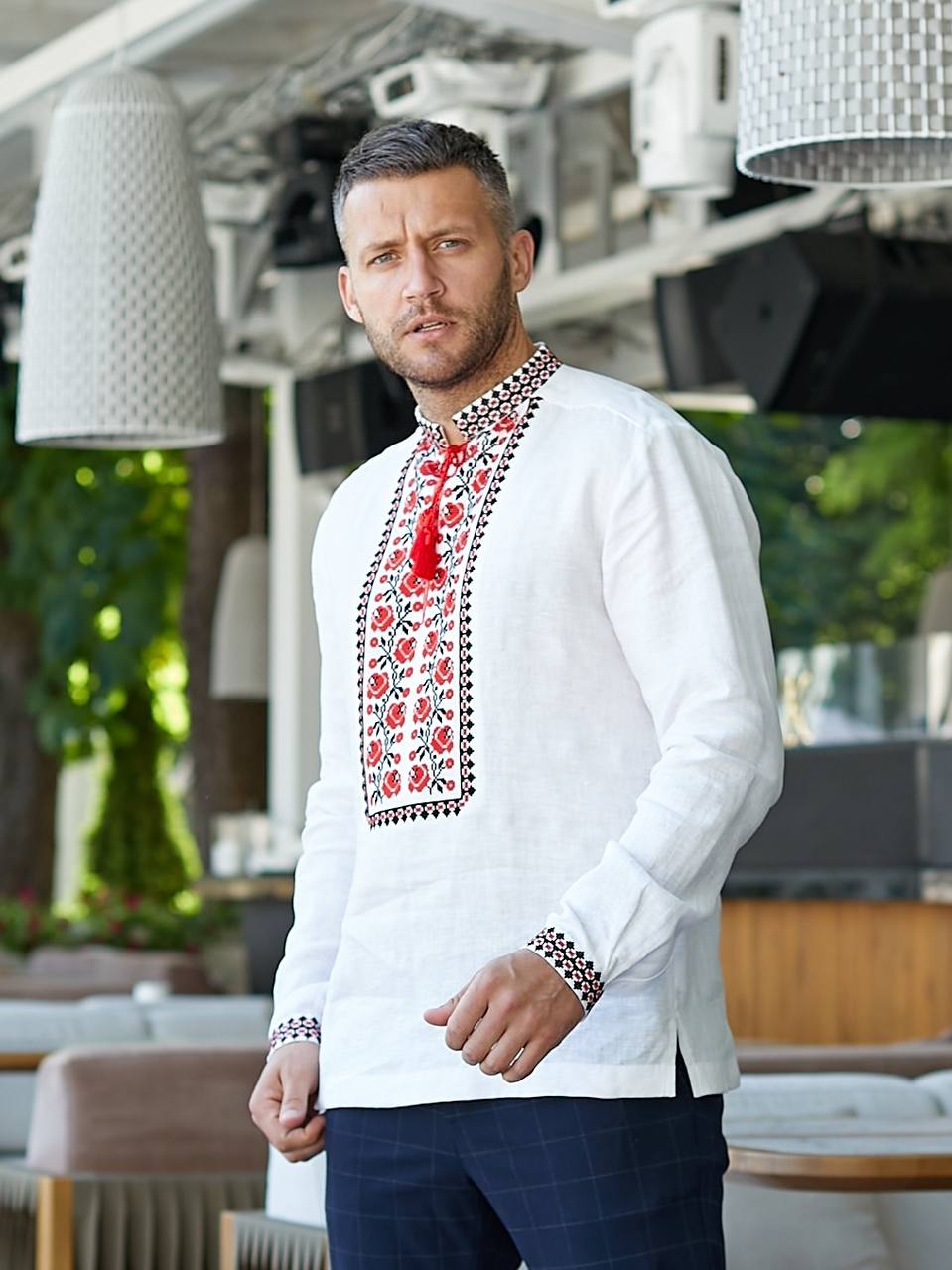 Man wearing a white embroidered shirt in an outdoor setting