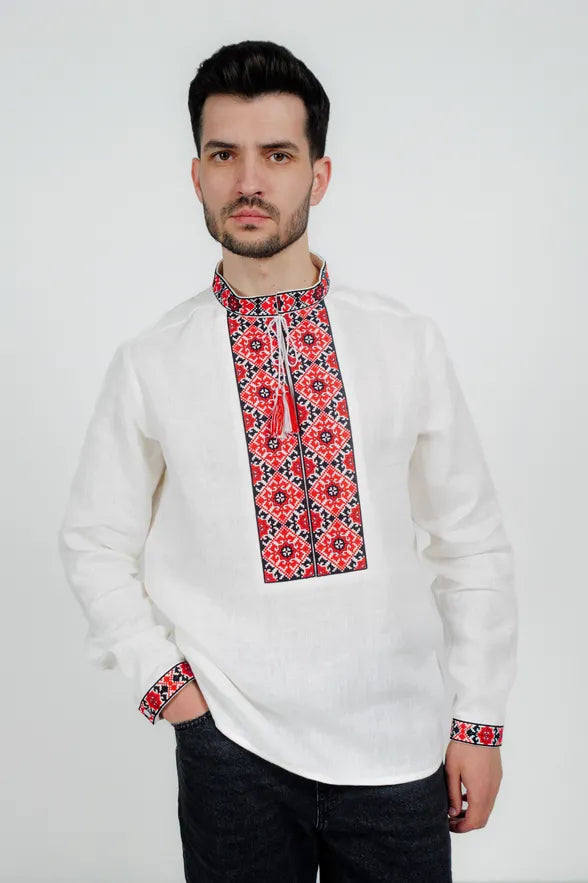 Man wearing a white shirt with red and black floral embroidery on a white background