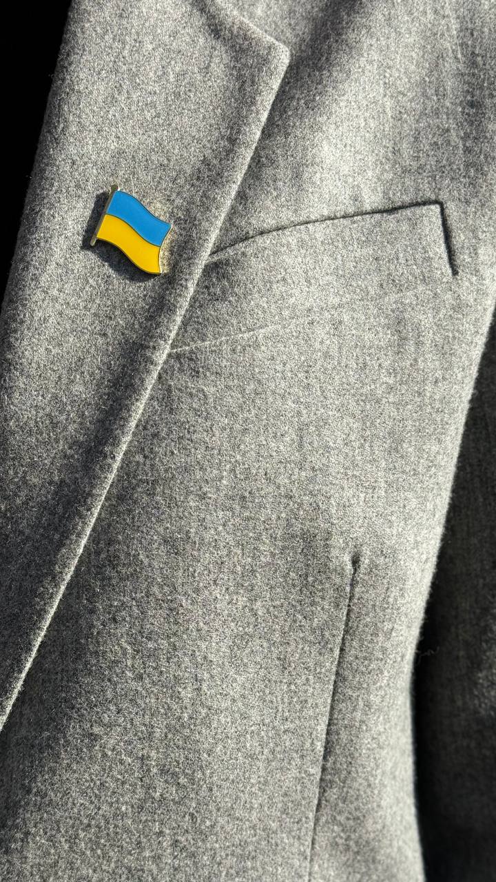 A pin with the Ukrainian flag colors attached to a grey fabric.