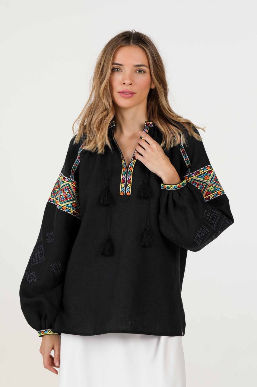 black linen blouse with colorful geometric embroidery on the shoulders and cuffs.