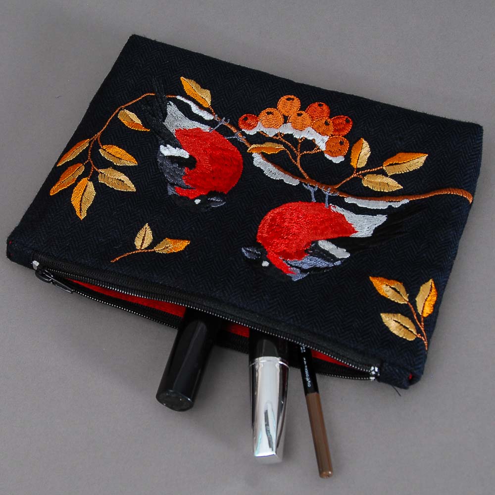 Embroidered pouch with floral and bird design on a gray background