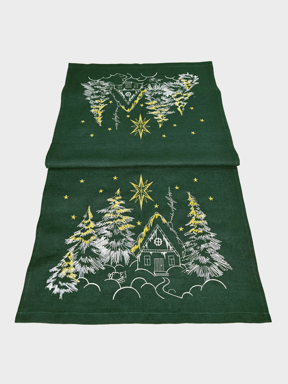 Green towel with embroidered design of a cabin and trees on a white background