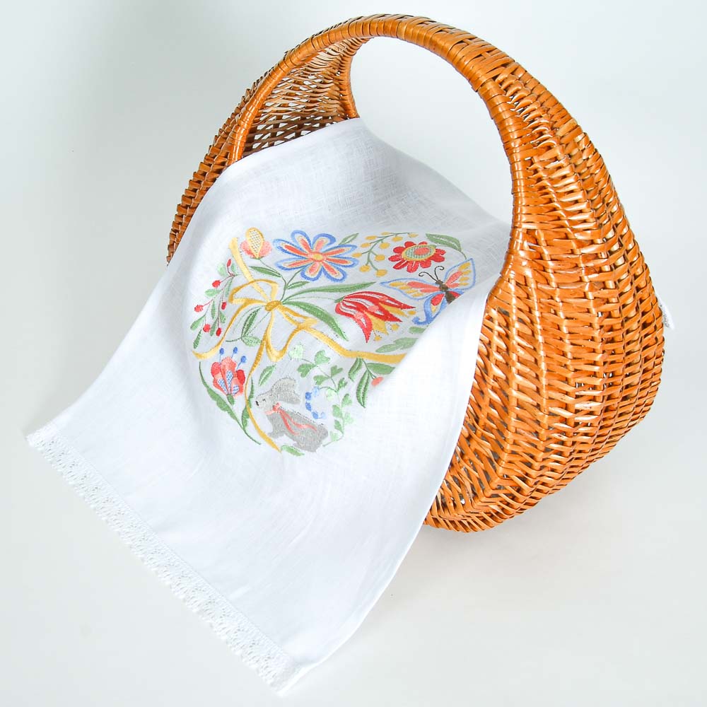 White towel with floral design in an orange wicker basket on a white background