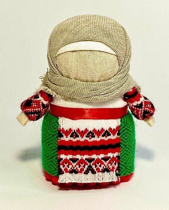 A handmade Ukrainian Motanka doll with a red, white, and green embroidered dress, and poppy seeds inside.