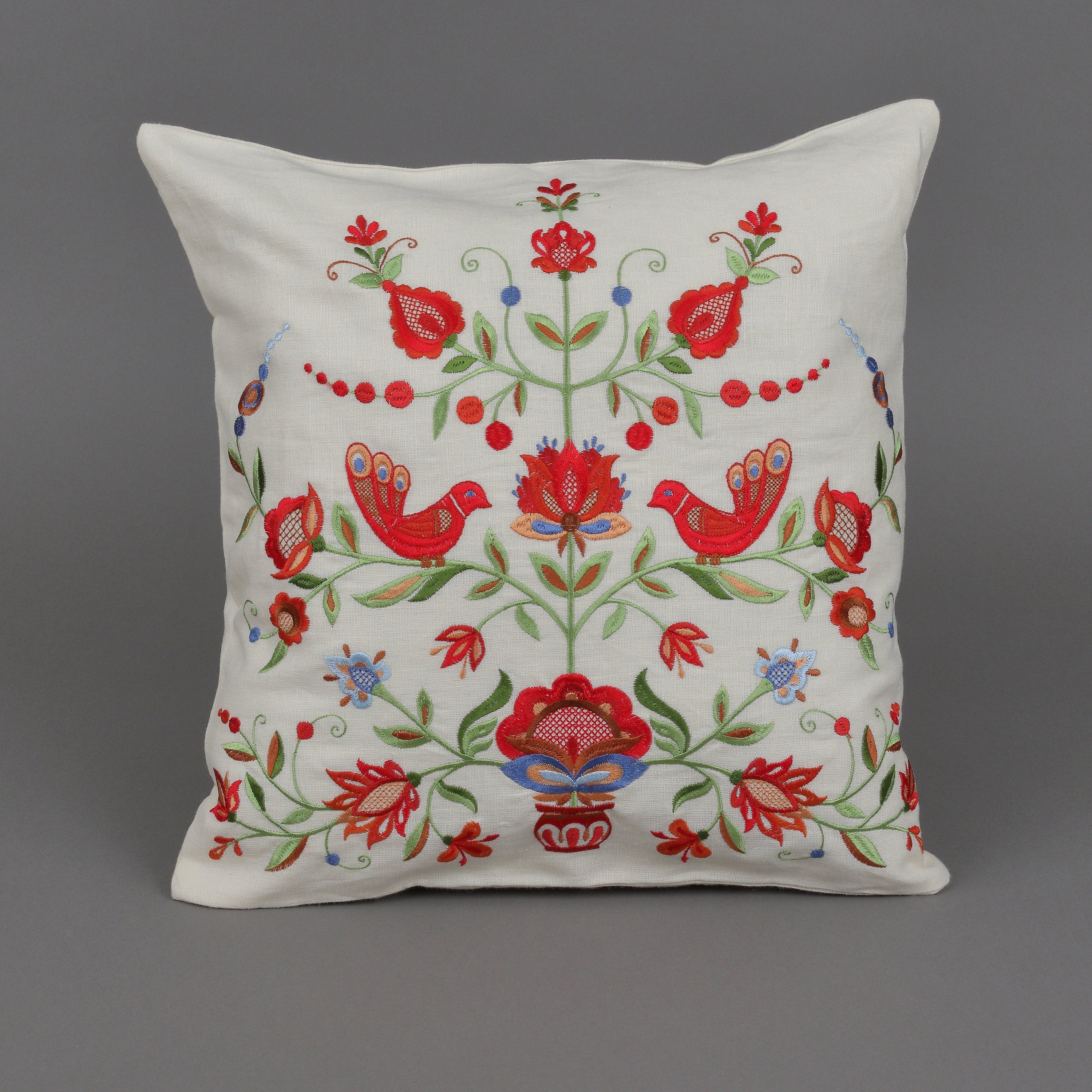 A square-shaped linen pillowcase with a floral embroidery design, featuring red and green colors with a bird motif.