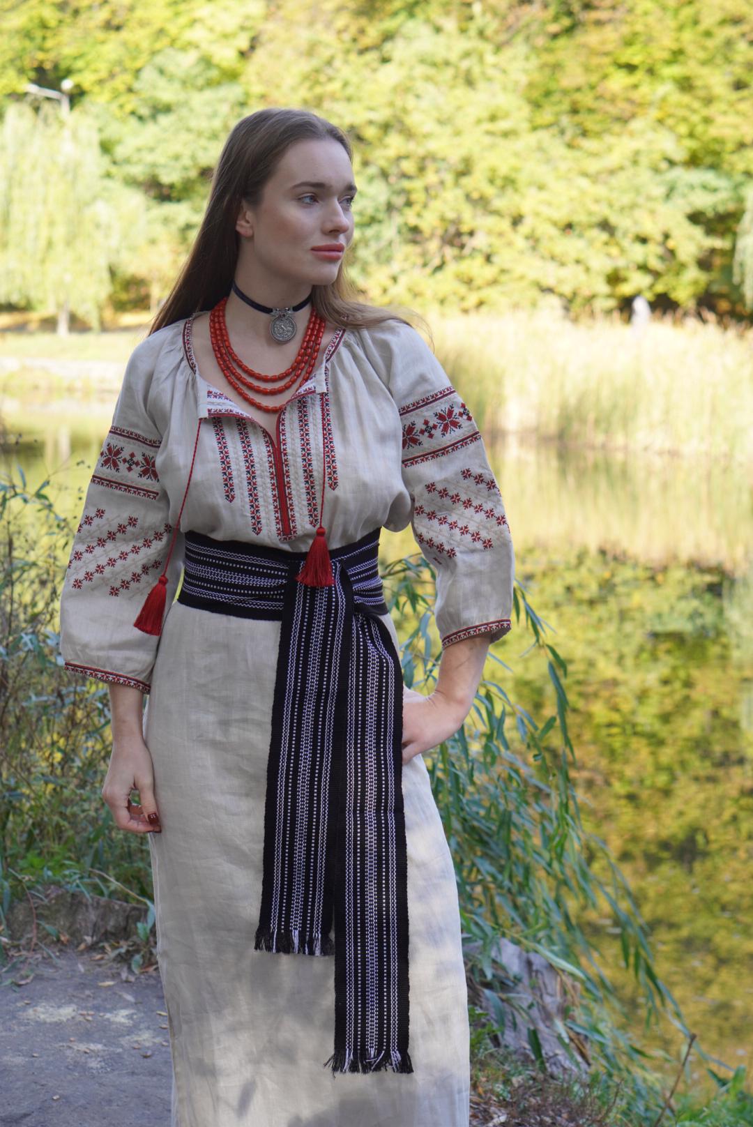 A person wearing a traditional Slavic costume with embroidery and a sash belt.